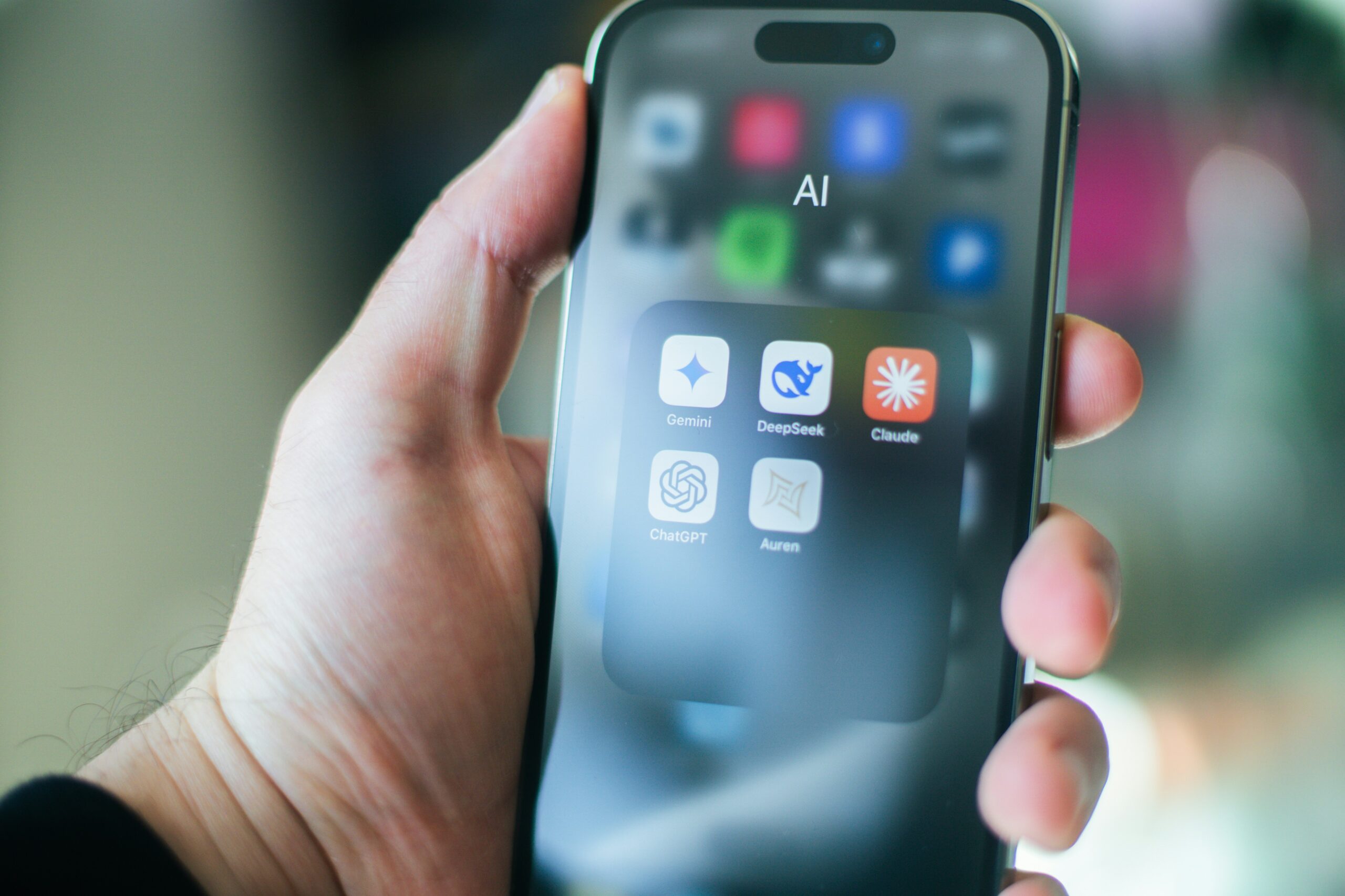 Person holding phone displaying AI apps. 