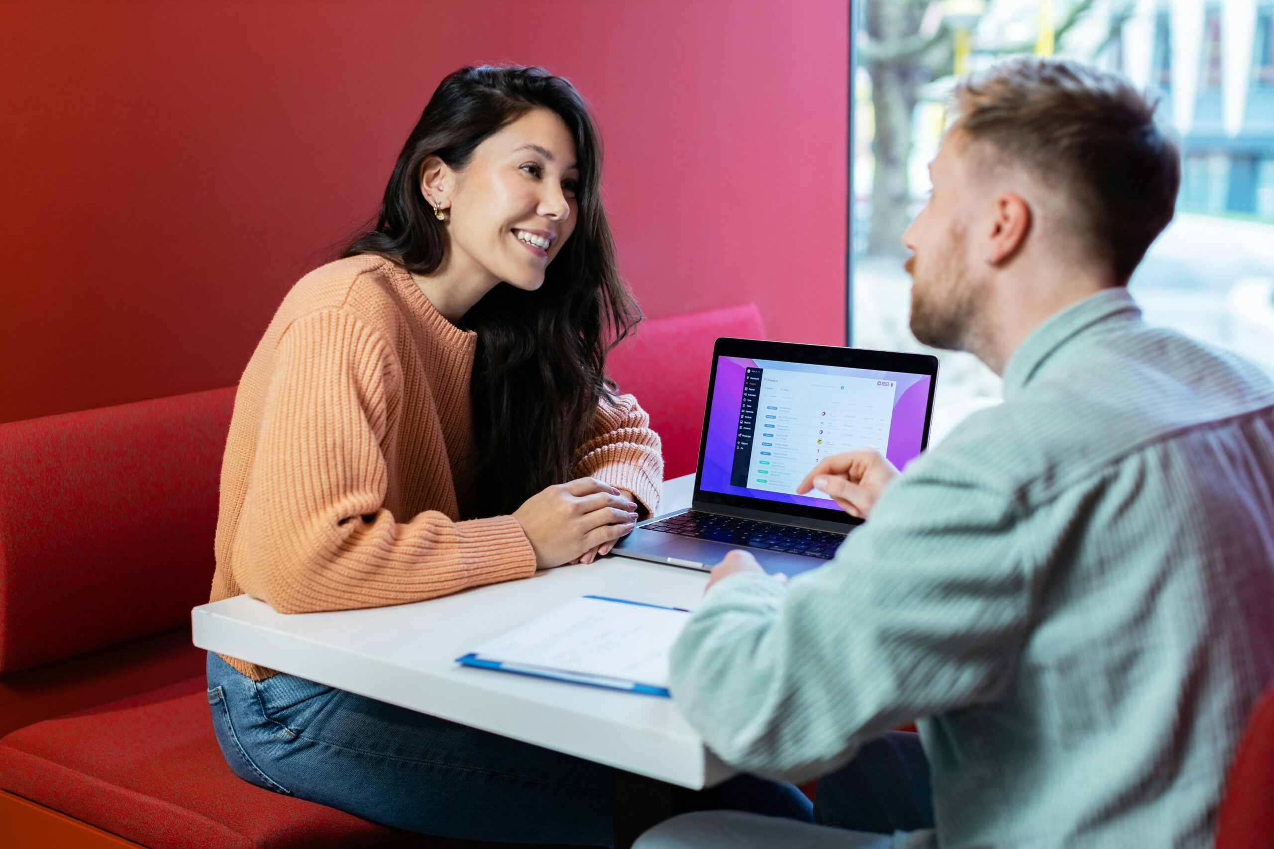 A man and woman having a meeting in front of a laptop.